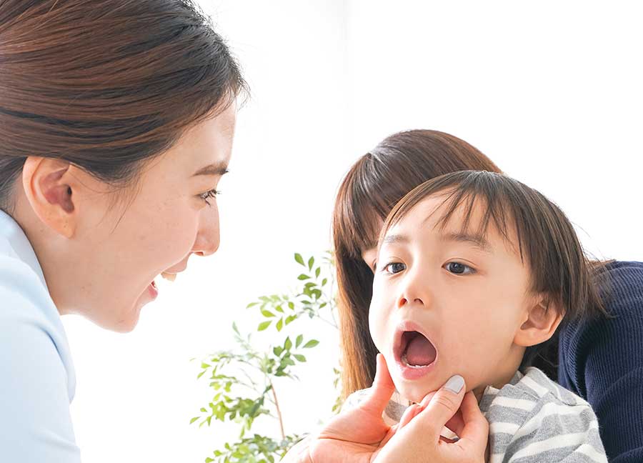 子供の口腔内を調べる歯科衛生士